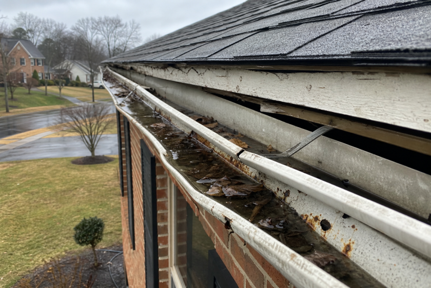 Damaged sagging gutters full of standing water and debris on Northern Virginia brick home