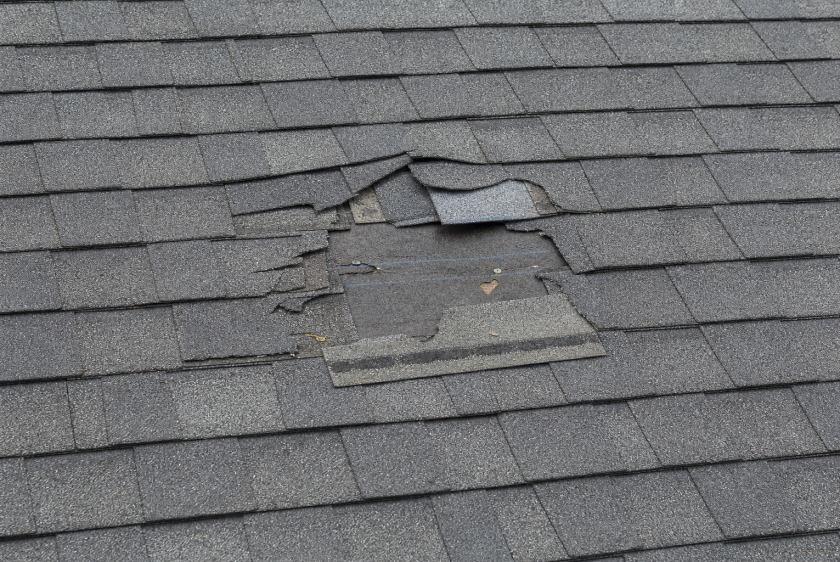 Localized roof repair area with missing and cracked asphalt shingles